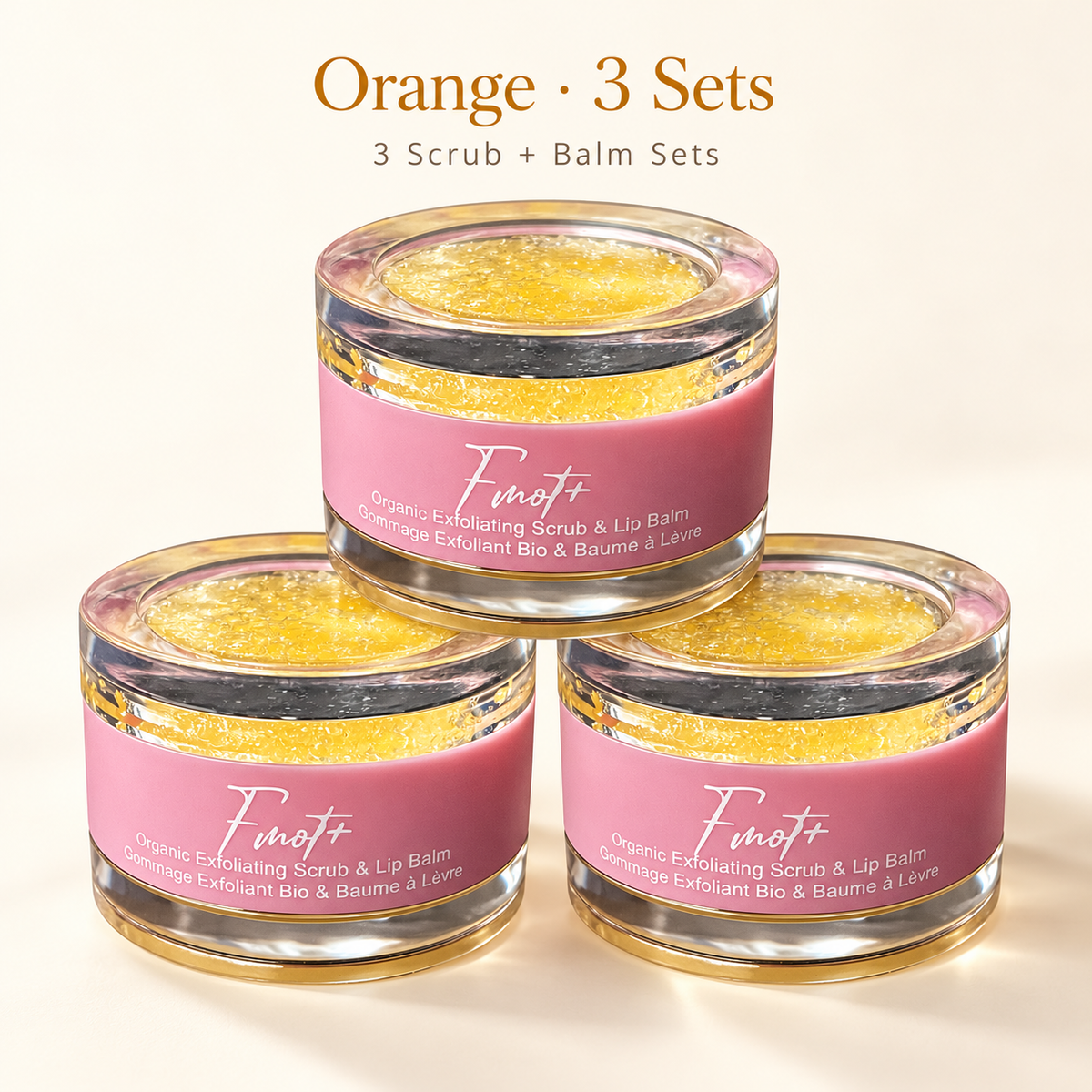 orange three lip scrub and balm set, with clear round packaging and pink label.