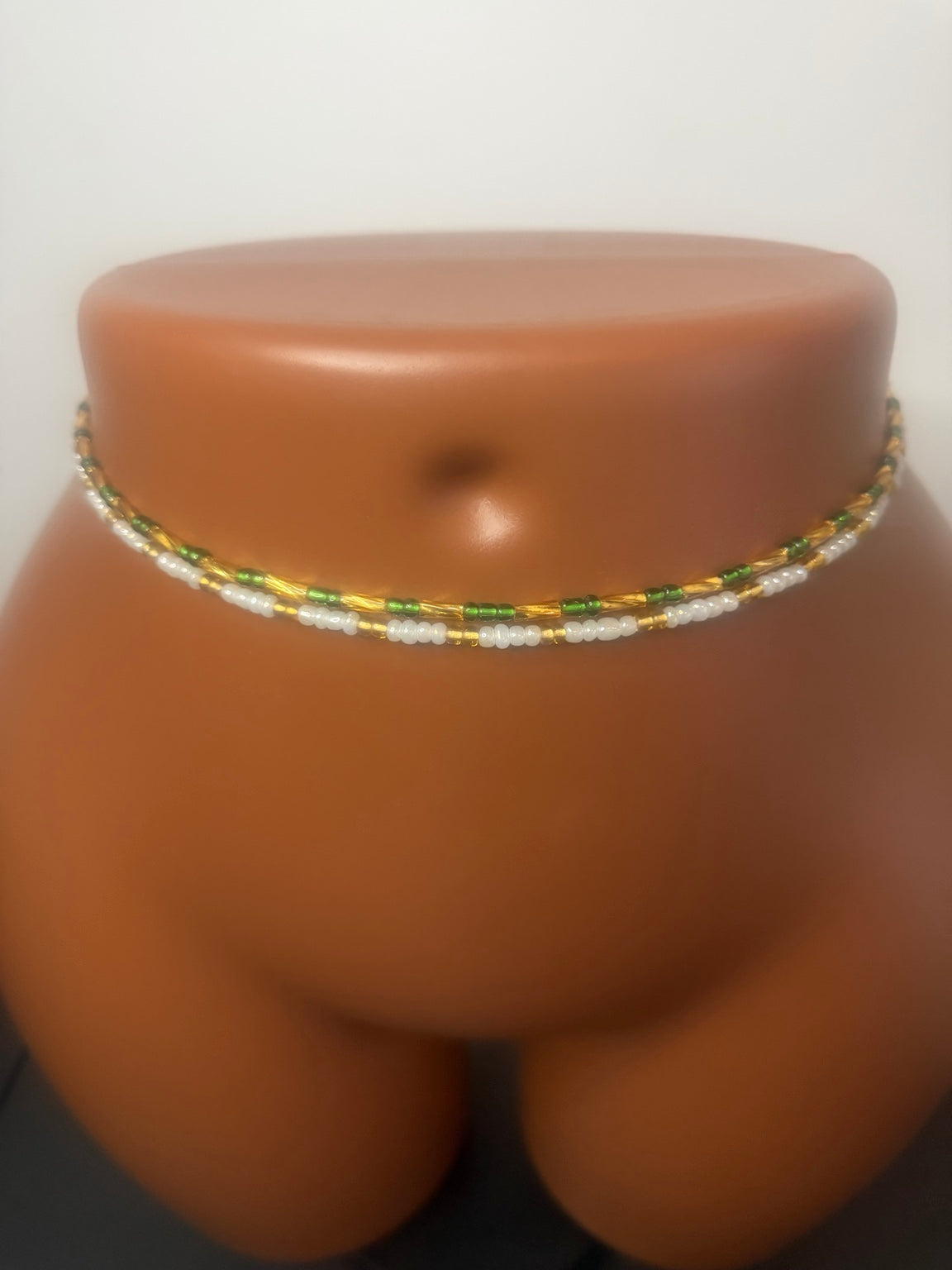 Emerald Duo: two separate tie-on waist bead strands in Emerald Green & Gold and Pearl & Gold, shown on a display mannequin.