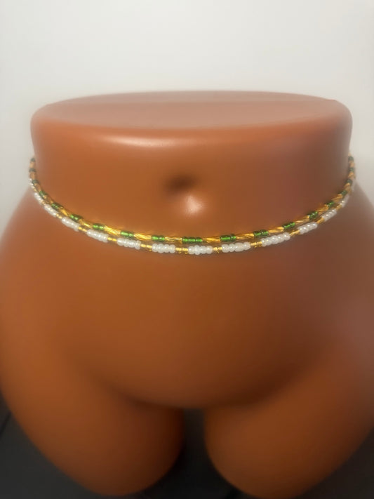 Emerald Duo: two separate tie-on waist bead strands in Emerald Green & Gold and Pearl & Gold, shown on a display mannequin.